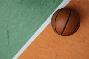 A close-up of a basketball resting on a colorful court with orange and green sections.