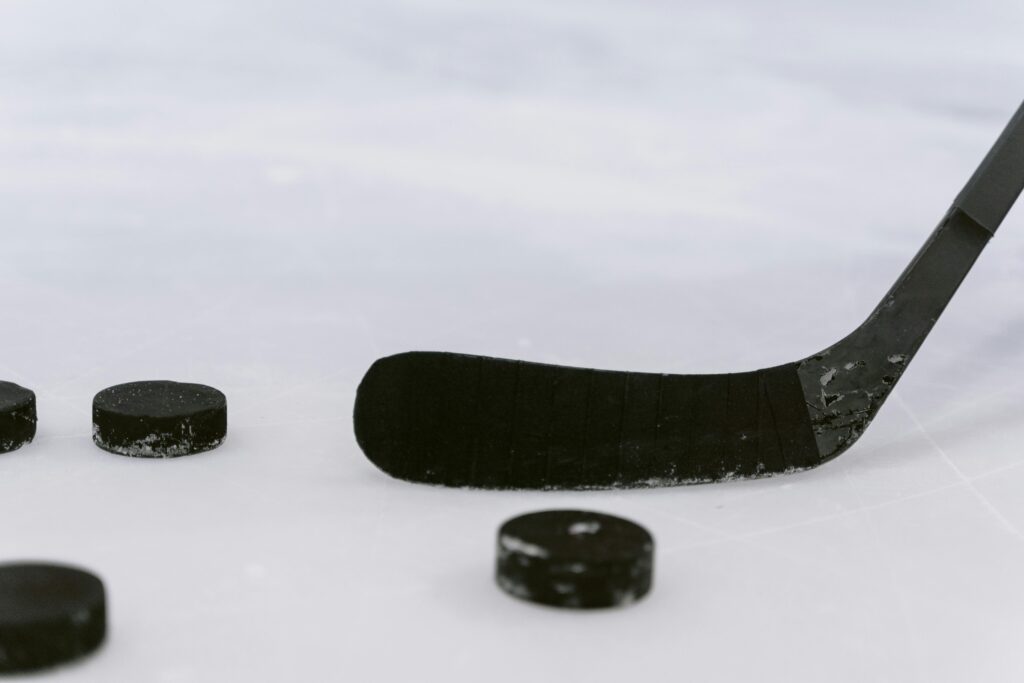 Detailed view of a hockey stick and pucks on ice, perfect for sports visuals.