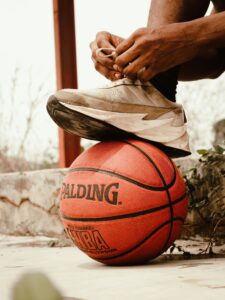 A close-up of a man tying his shoe on a basketball, depicting athletic preparation.