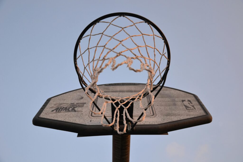 Close-up view of a basketball hoop and net against a clear sky, ideal for sports and leisure themes.
