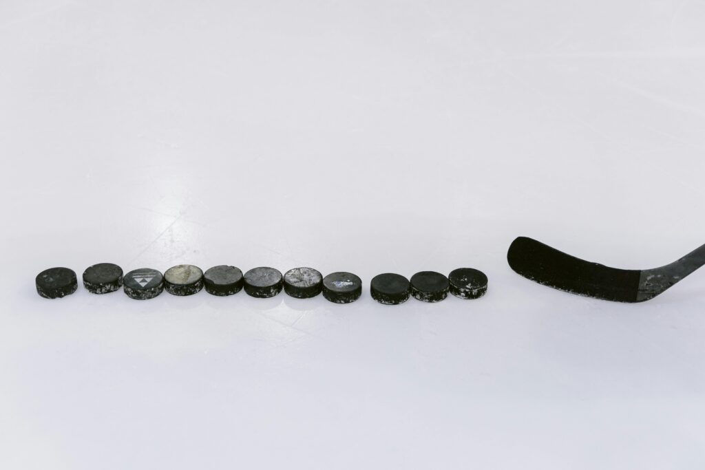 A row of hockey pucks and a stick on an ice rink, perfect for sports content.